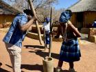 Pounding grains to make a fine maize meal. You must find a good rhythm to not hit your partner's staff!