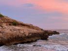 A beautiful colorful sunset on a rocky beach in Sitges, Spain