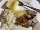 Un plato de churrasco completo con mandioca, arroz y verduras