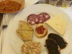 Tasting some appetizers, like cheese, salami and bread topped with olive oil, olive paste, beans and tomato!