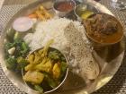 Chicken curry, rice, greens and more on a brass plate