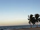 The moon visible over the Caribbean Sea during sunset.