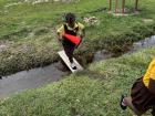 A student walking over a flooded path on a plank.