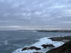 A view of the beach, with the Tower of Hercules off in the distance