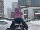 A bundled up dad and daughter walk to the store while it snows.