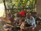 Four people preparing chicken by hand for a party
