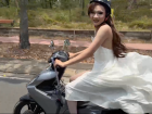 A local Vietnamese woman rides a motorbike wearing a flowing white dress