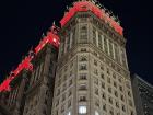 A pretty building with red lights at night. 