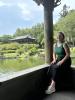 Sitting in a gazebo by the pond in the National Palace Museum with lots of green plants and trees as well as a beautifully detailed gazebo in the background