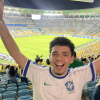 Guy (me) standing in front of Brazil's Maracana Stadium, with arms up cheering